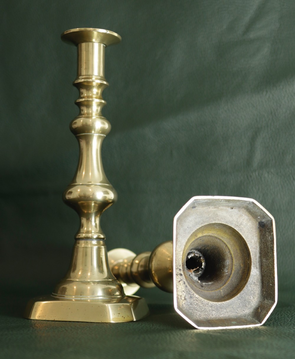 A pair of polished brass candlesticks featuring teardrop baluster columns resting on octagonal stepped bases. View II