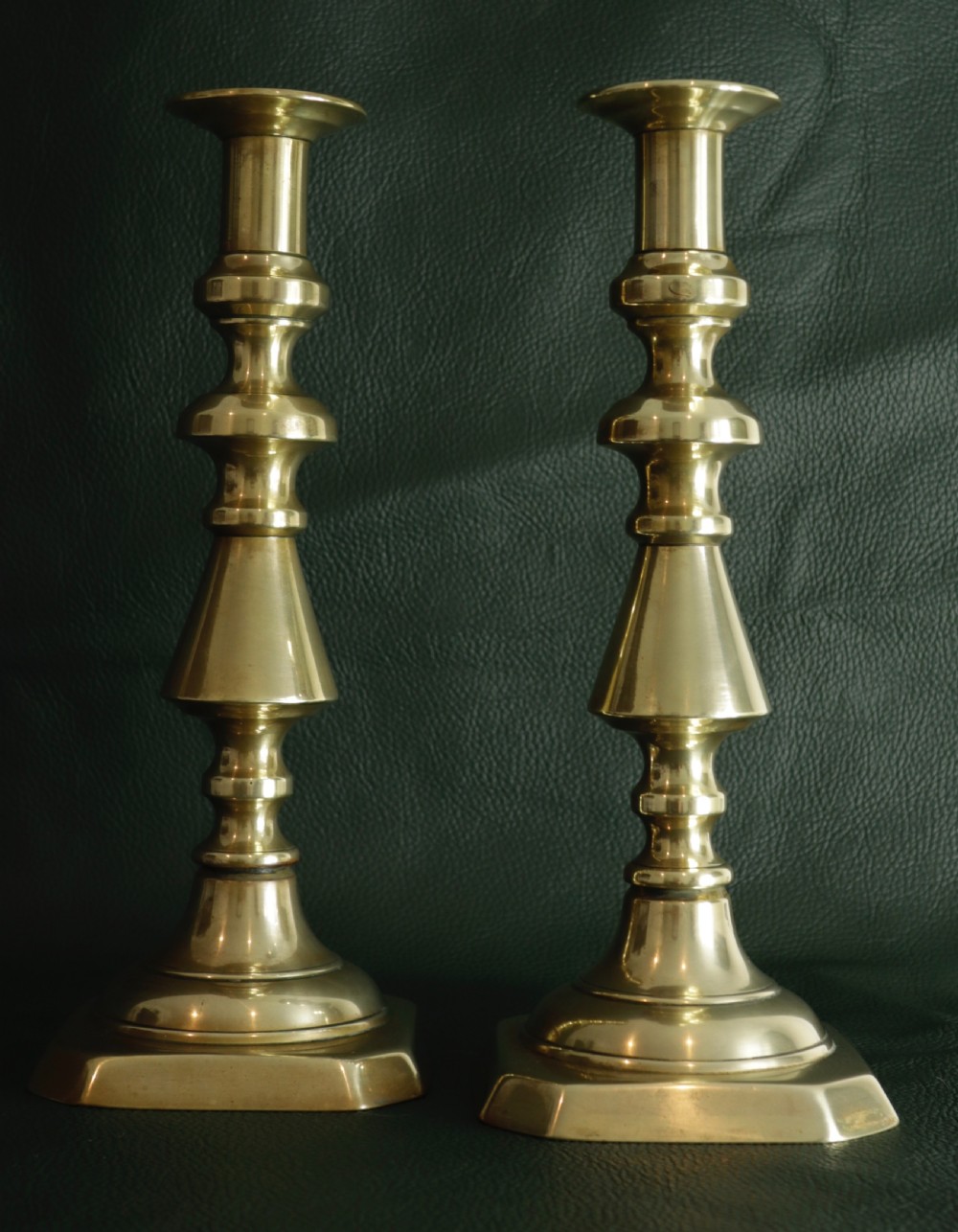 A pair of turned antique brass candlesticks featuring knopped stems and stepped octagonal bases.