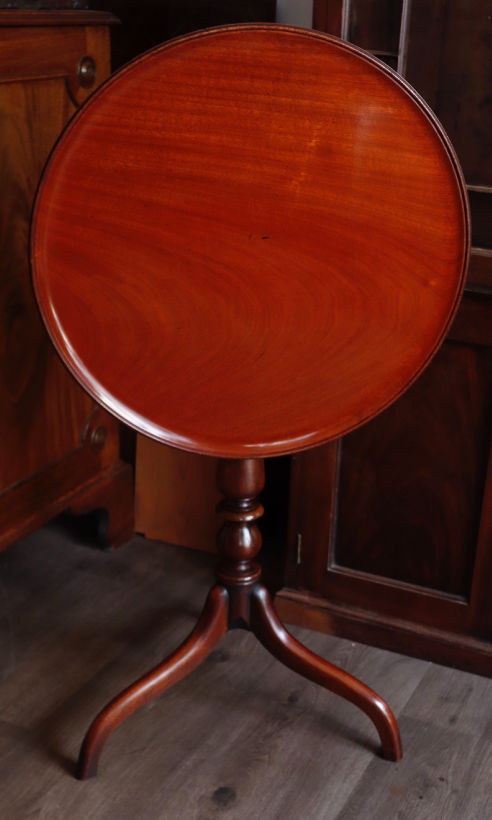 A polished mahogany tripod table with a circular top, turned central column, and three curved legs. View VI