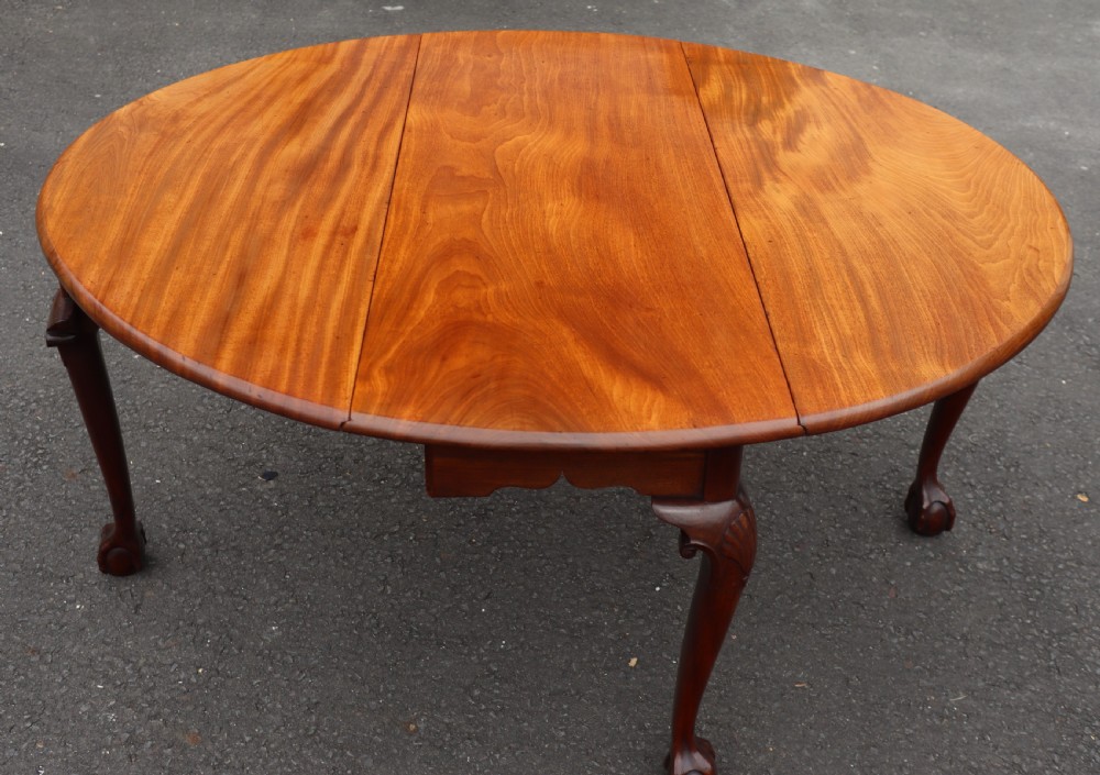An antique mahogany drop-leaf dining table featuring carved cabriole legs terminating in claw and ball feet. View II