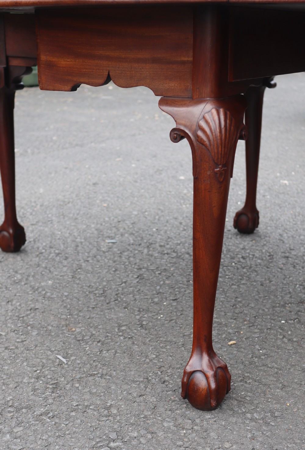 An antique mahogany drop-leaf dining table featuring carved cabriole legs terminating in claw and ball feet. View III