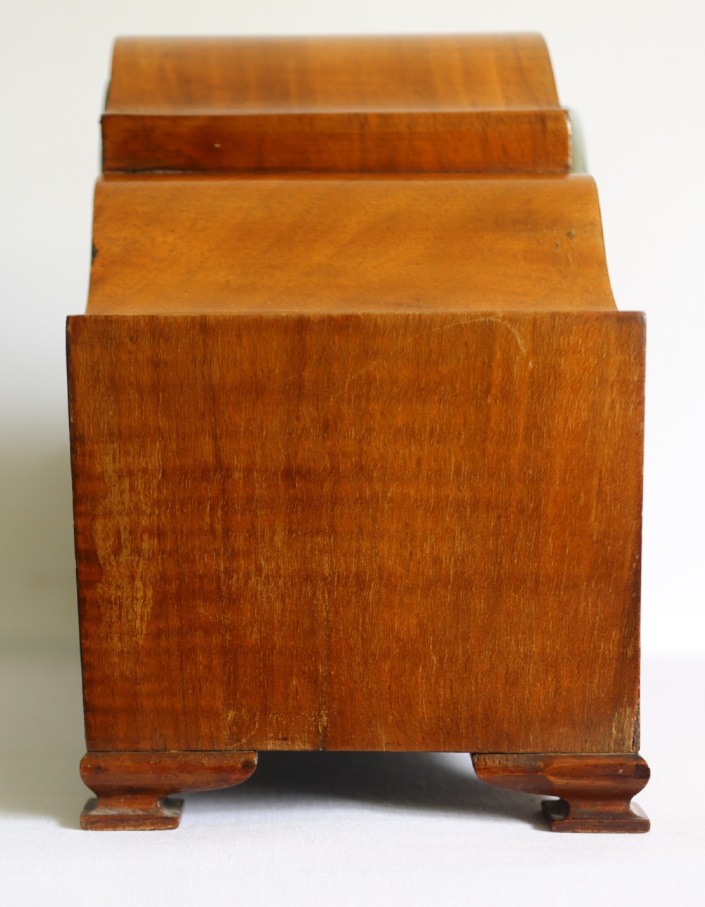 An Art Deco wooden mantel clock featuring an arched case with book-matched veneer and a round silvered dial with Arabic numerals. View V