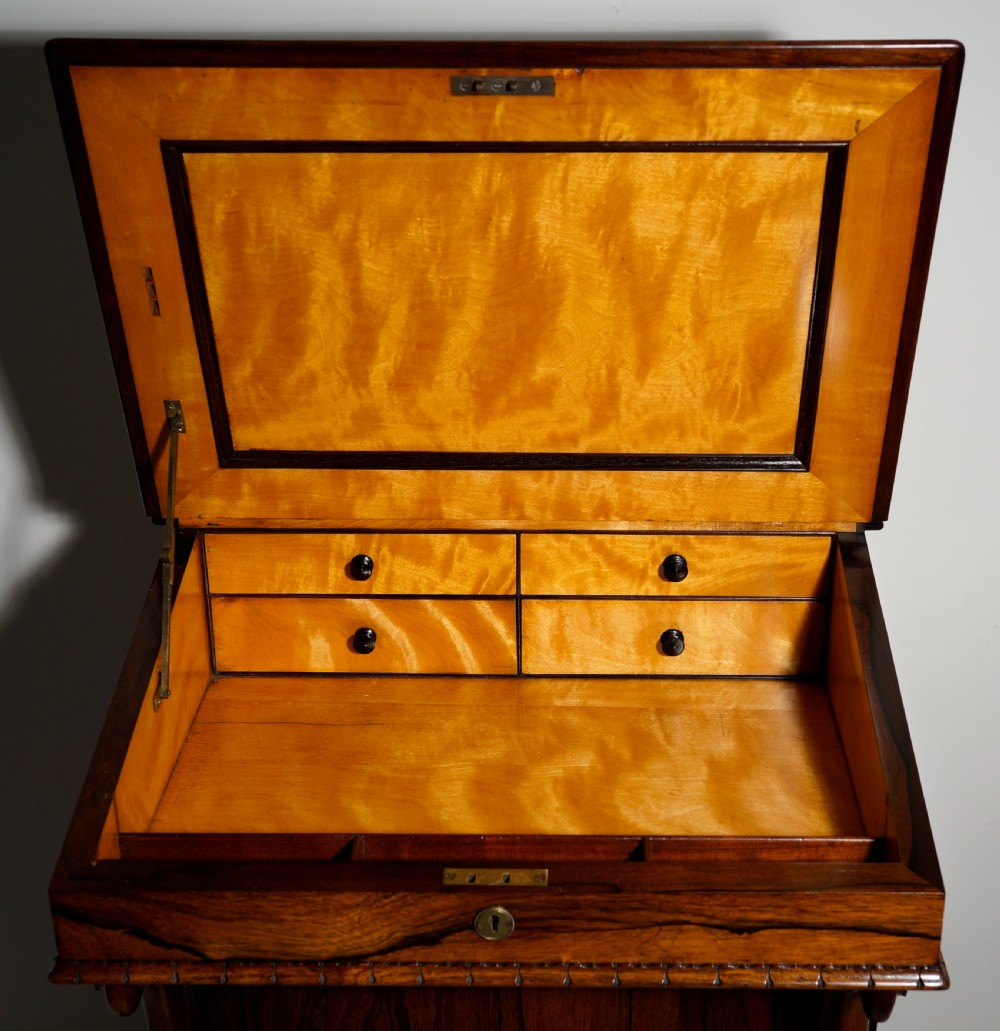 A dark brown rosewood Davenport desk featuring carved scroll front supports, side drawer panelling, and a slanted writing top. View III