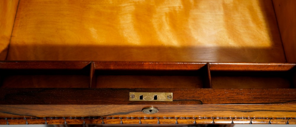 A dark brown rosewood Davenport desk featuring carved scroll front supports, side drawer panelling, and a slanted writing top. View XII