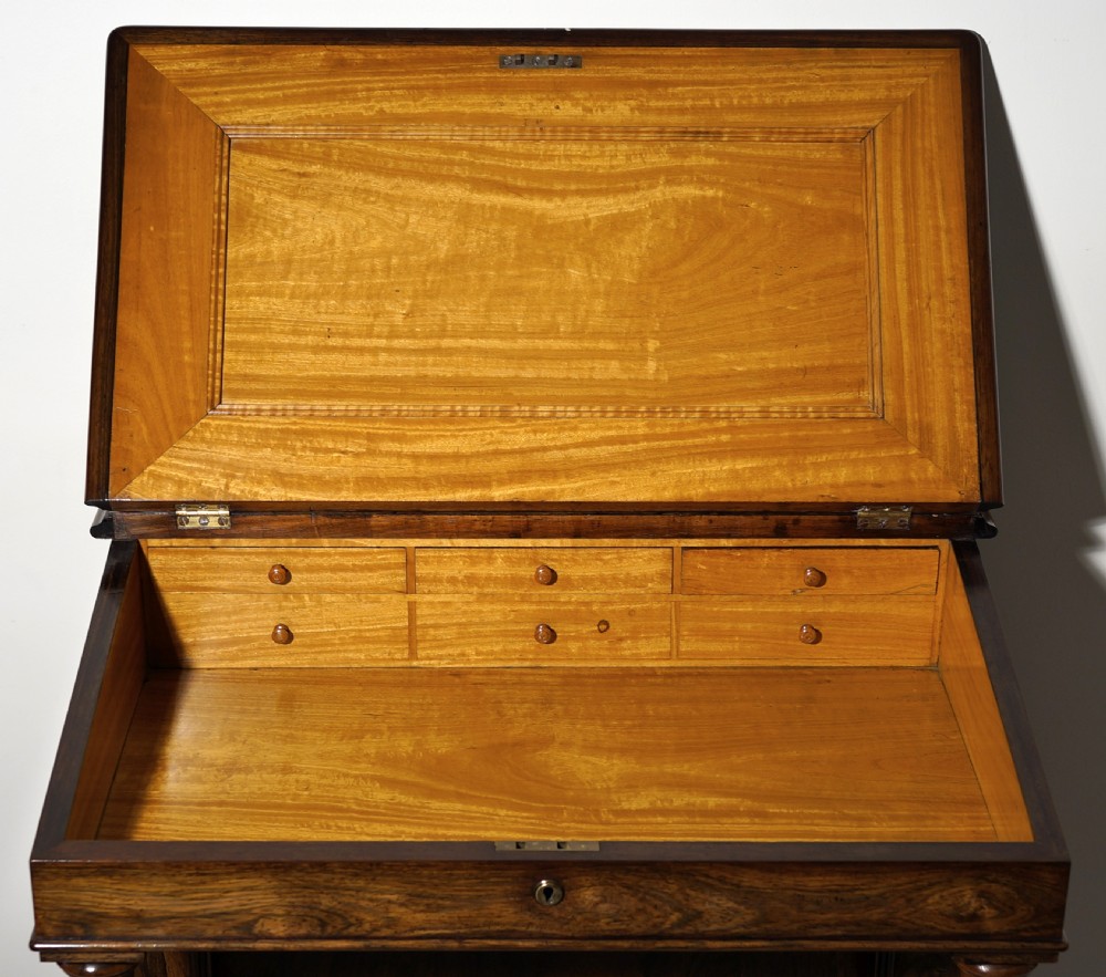 An antique Victorian rosewood Davenport desk featuring a slanted black leather writing surface, a pierced top gallery rail, and turned barley twist front columns. View II