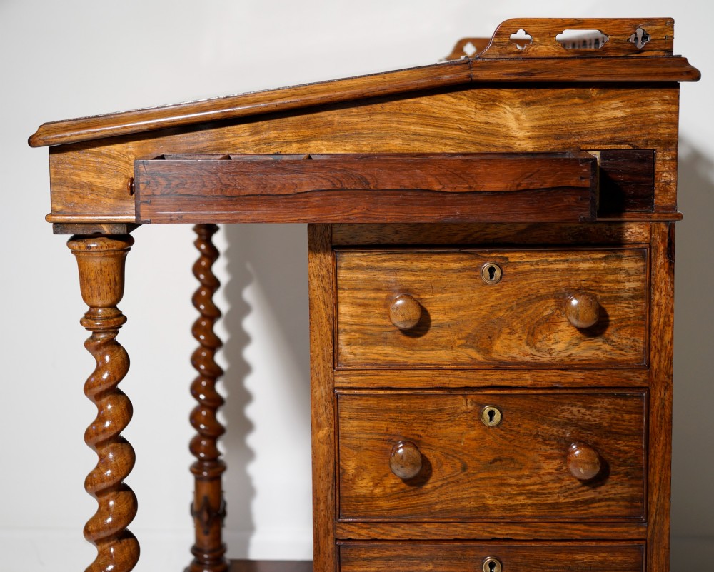 An antique Victorian rosewood Davenport desk featuring a slanted black leather writing surface, a pierced top gallery rail, and turned barley twist front columns. View IV