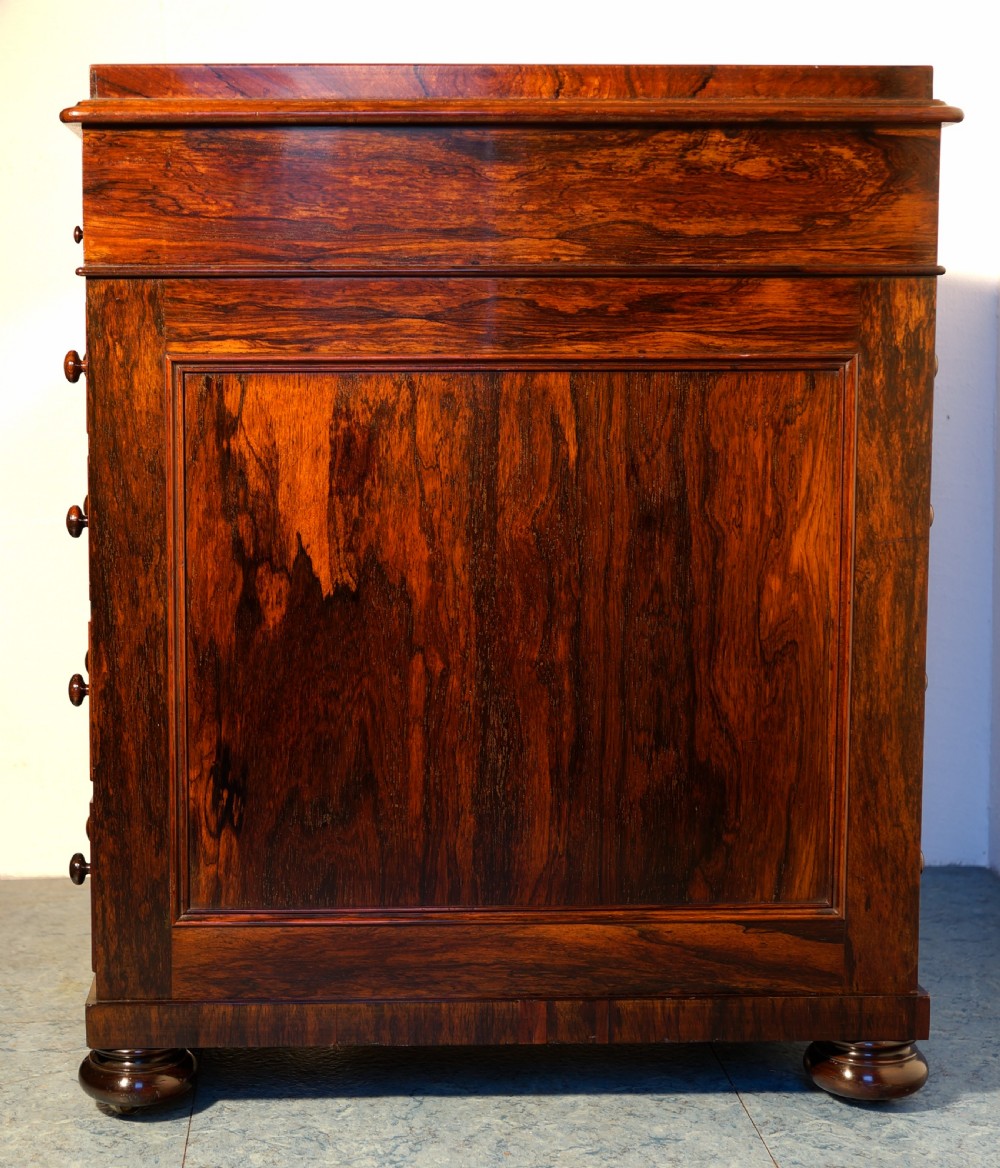 A Victorian dark rosewood Davenport desk featuring spiral turned supports, a sloped writing lid, and a side column of four drawers with turned wooden knobs. View V