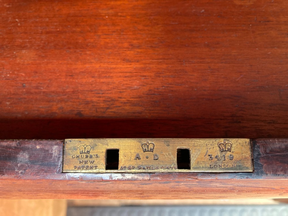 A mahogany writing desk featuring floral marquetry swags, seven drawers with brass handles, a central arch kneehole, and tapered legs on brass castors. View III