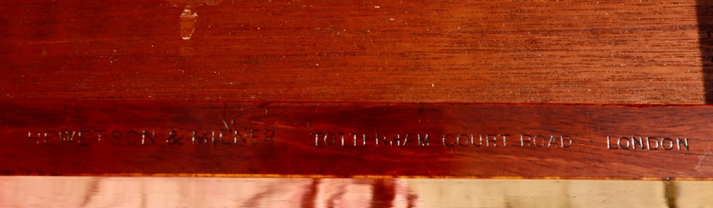 A mahogany writing desk featuring floral marquetry swags, seven drawers with brass handles, a central arch kneehole, and tapered legs on brass castors. View VII