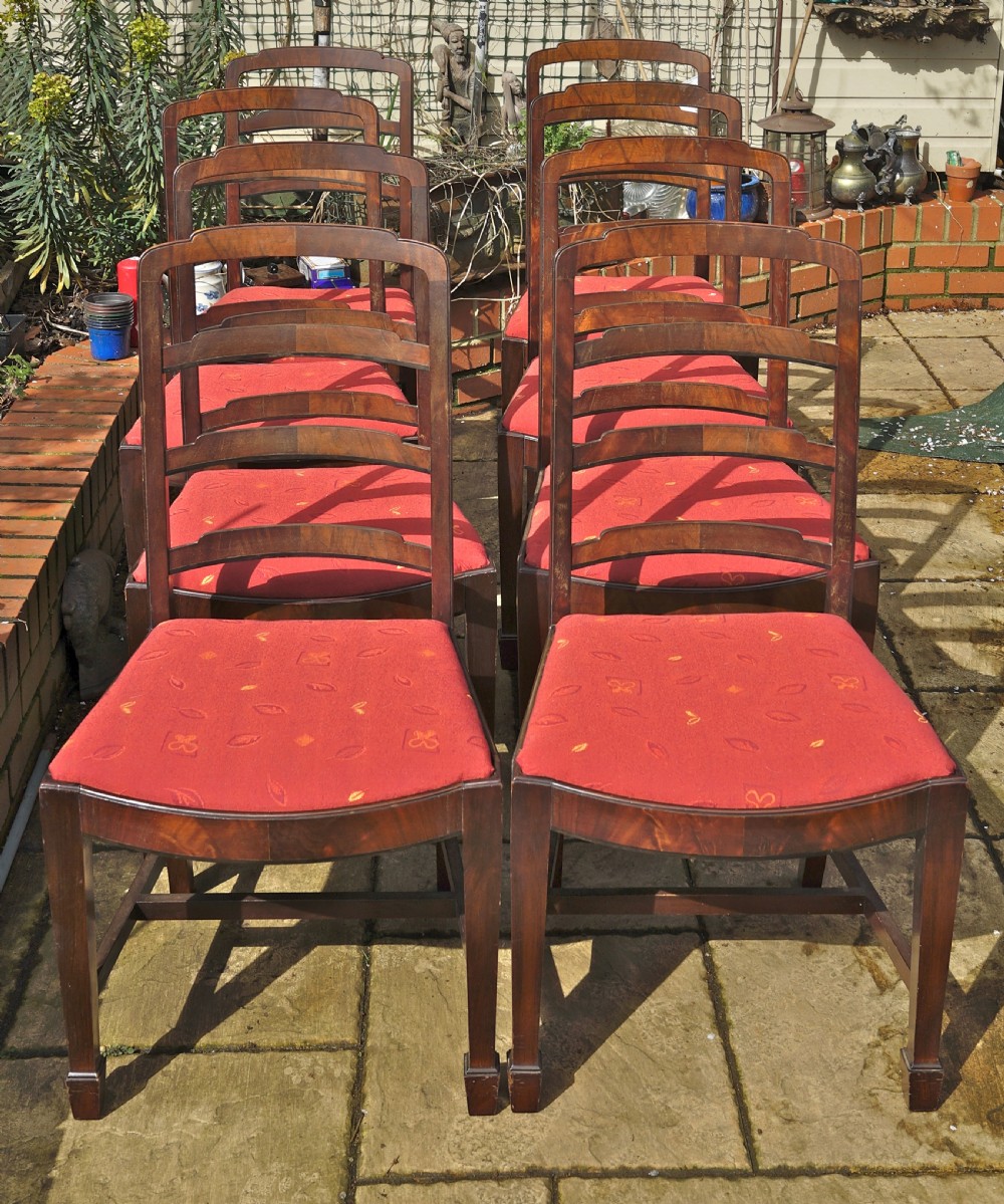 A set of eight mahogany dining chairs featuring arched ladder backs and red patterned fabric upholstered seats.