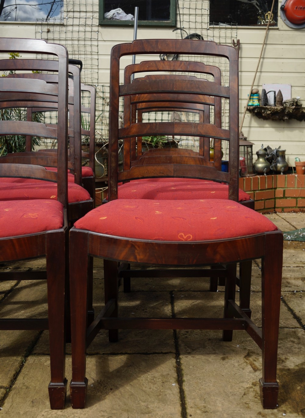 A set of eight mahogany dining chairs featuring arched ladder backs and red patterned fabric upholstered seats. View II
