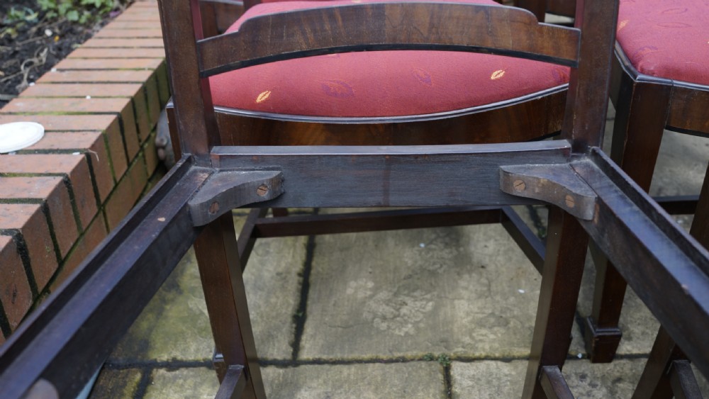 A set of eight mahogany dining chairs featuring arched ladder backs and red patterned fabric upholstered seats. View IV