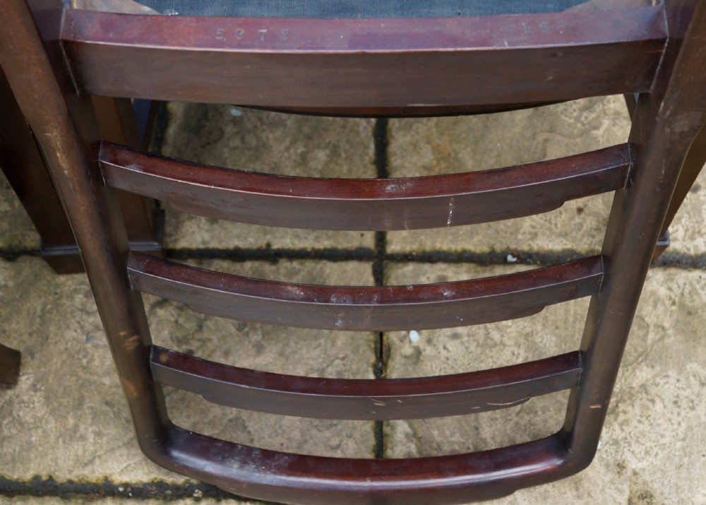 A set of eight mahogany dining chairs featuring arched ladder backs and red patterned fabric upholstered seats. View VI