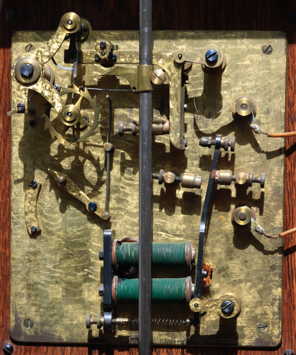 An antique oak longcase clock featuring a circular brass dial with Roman numerals and a full-length glazed trunk door revealing the pendulum and movement. View V