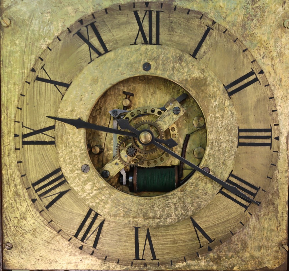 An antique oak longcase clock featuring a circular brass dial with Roman numerals and a full-length glazed trunk door revealing the pendulum and movement. View VII