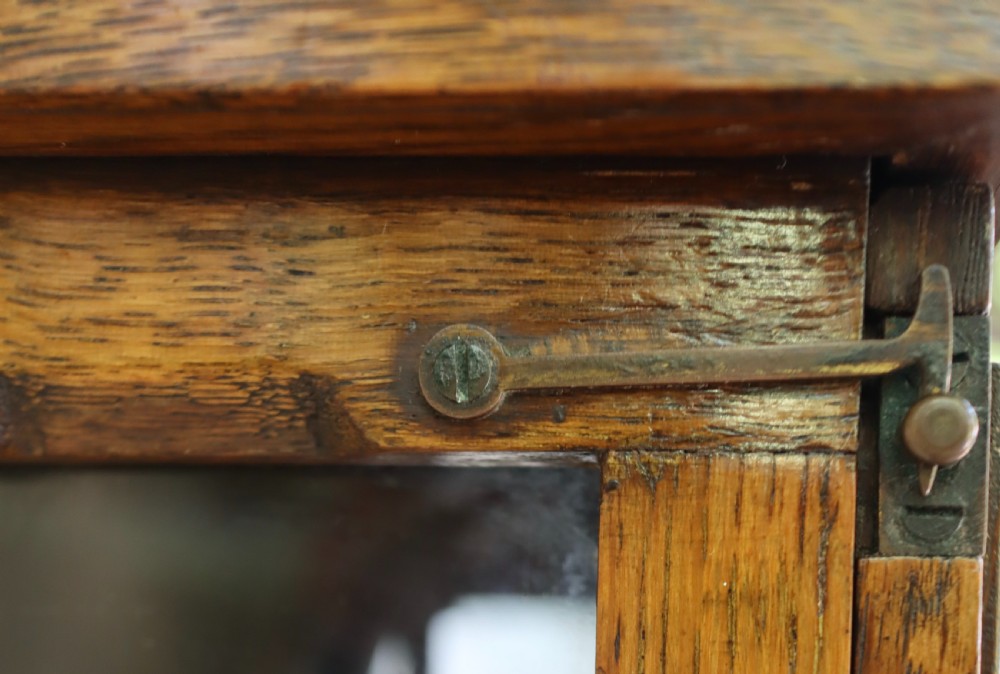 An antique oak longcase clock featuring a circular brass dial with Roman numerals and a full-length glazed trunk door revealing the pendulum and movement. View XI