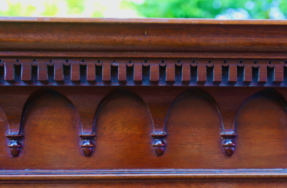 A tall, free-standing antique mahogany corner cupboard featuring two stacked panel doors decorated with carved corner details and top dentil moulding. View VI
