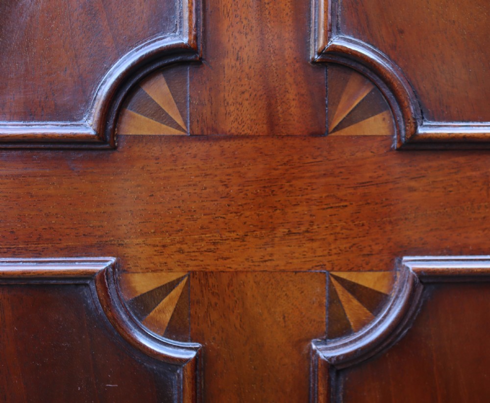A tall, free-standing antique mahogany corner cupboard featuring two stacked panel doors decorated with carved corner details and top dentil moulding. View VII