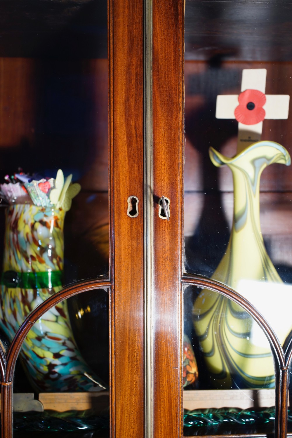 An antique mahogany bureau bookcase with astragal glazed doors above a slant-front writing desk and three lower drawers with brass handles. View X