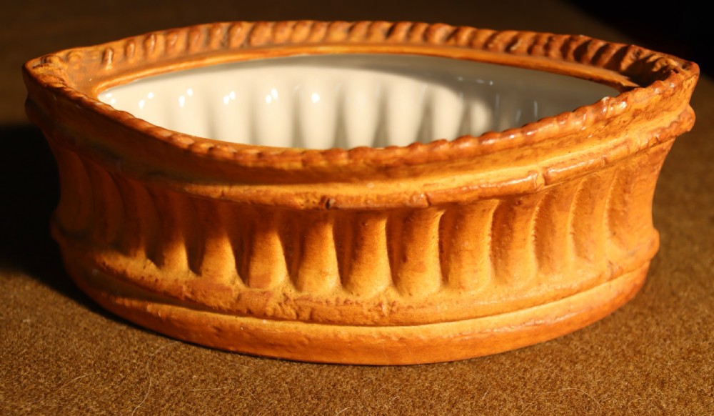 An oval terracotta game pie dish featuring a fluted base and a woven pastry lid topped with a painted bird head finial. View III