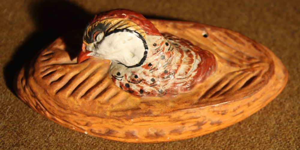 An oval terracotta game pie dish featuring a fluted base and a woven pastry lid topped with a painted bird head finial. View VII