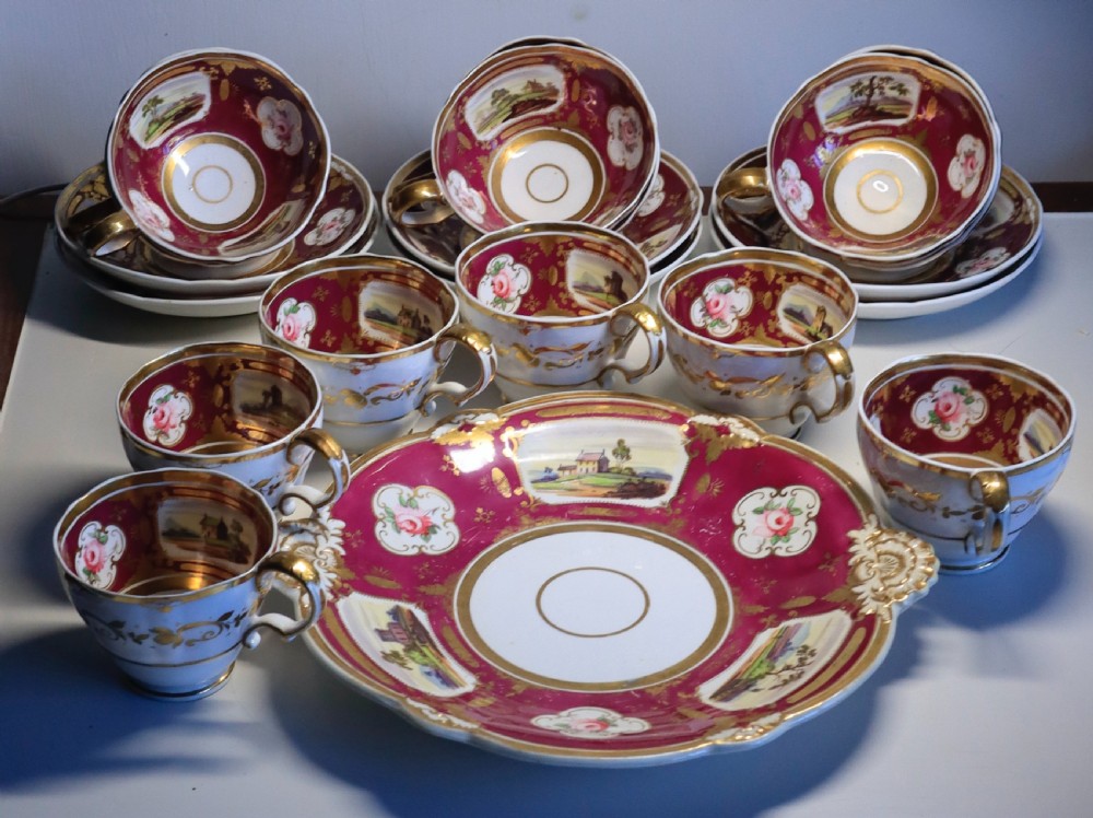 An antique Regency-era Hicks, Meigh & Johnson porcelain tea service featuring crimson ground panels, hand-painted landscape scenes, floral vignettes, and heavy gold leaf gilding.