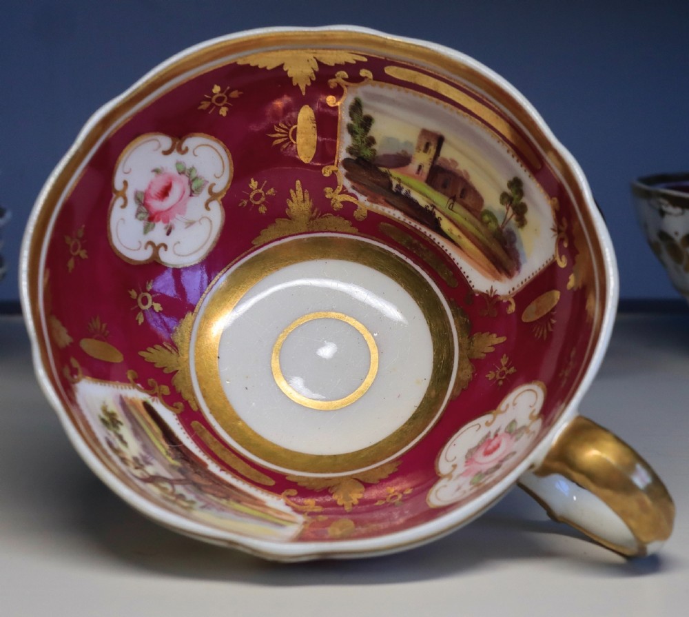 An antique Regency-era Hicks, Meigh & Johnson porcelain tea service featuring crimson ground panels, hand-painted landscape scenes, floral vignettes, and heavy gold leaf gilding. View X