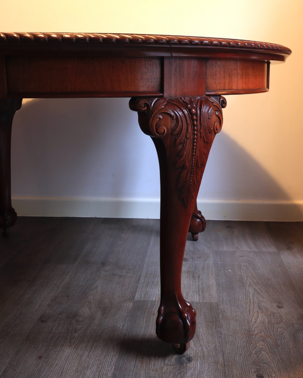 A circular mahogany antique extending dining table featuring carved cabriole legs with ball and claw feet and a rope-carved rim edge. View II