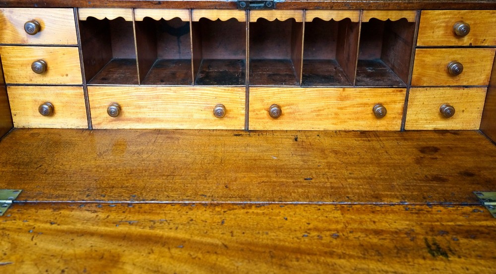 A Georgian mahogany slant-front bureau desk featuring four graduated drawers with oval brass handles on a bracket feet base. View III