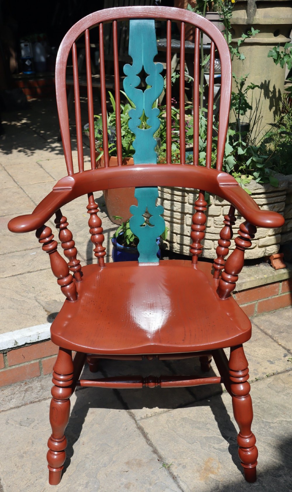 A Victorian hoop-back Windsor armchair painted in terracotta red with a central pierced splat highlighted in teal green.