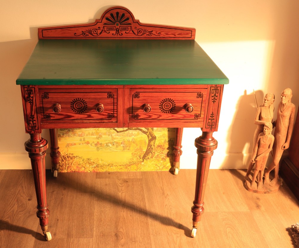 A late Victorian Aesthetic Movement pitch pine side table with a green surface, ebonised geometric incised patterns, two drawers, and turned legs with castors.