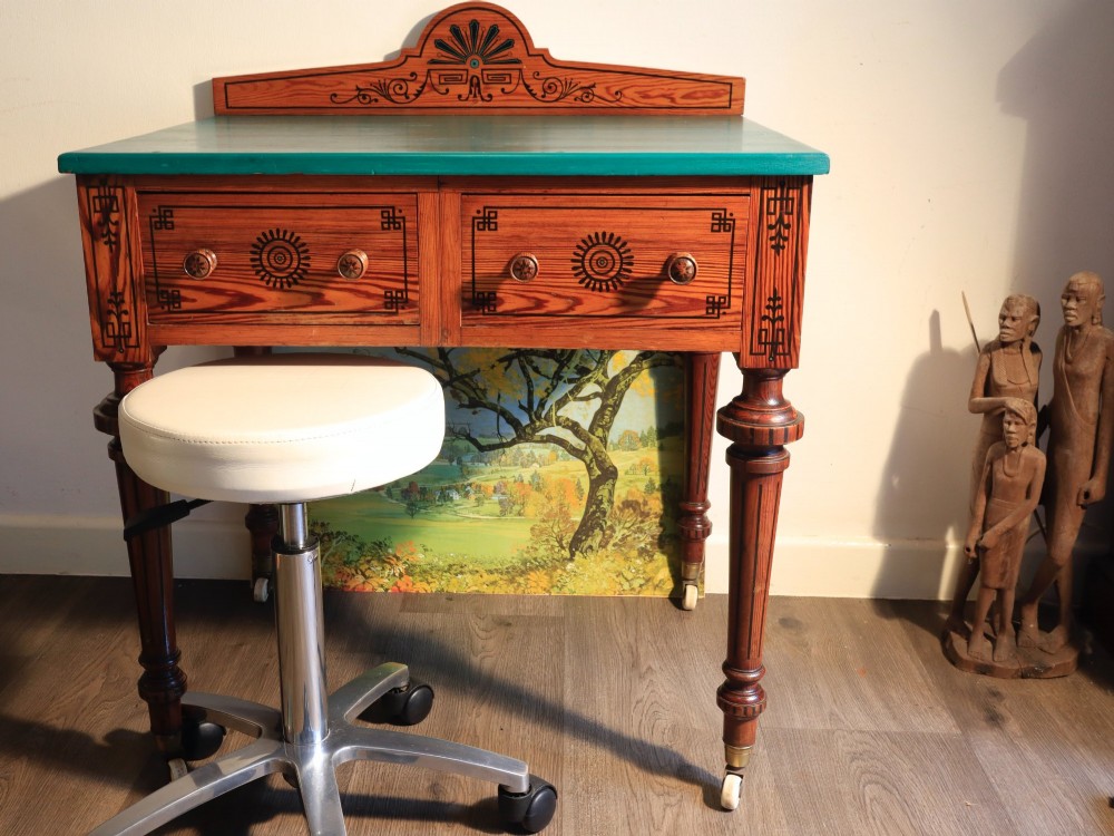 A late Victorian Aesthetic Movement pitch pine side table with a green surface, ebonised geometric incised patterns, two drawers, and turned legs with castors. View III