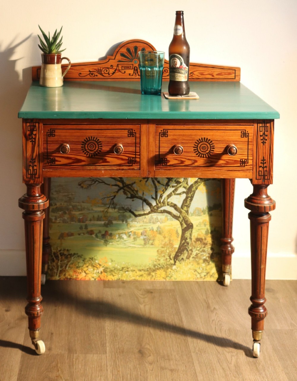 A late Victorian Aesthetic Movement pitch pine side table with a green surface, ebonised geometric incised patterns, two drawers, and turned legs with castors. View VI