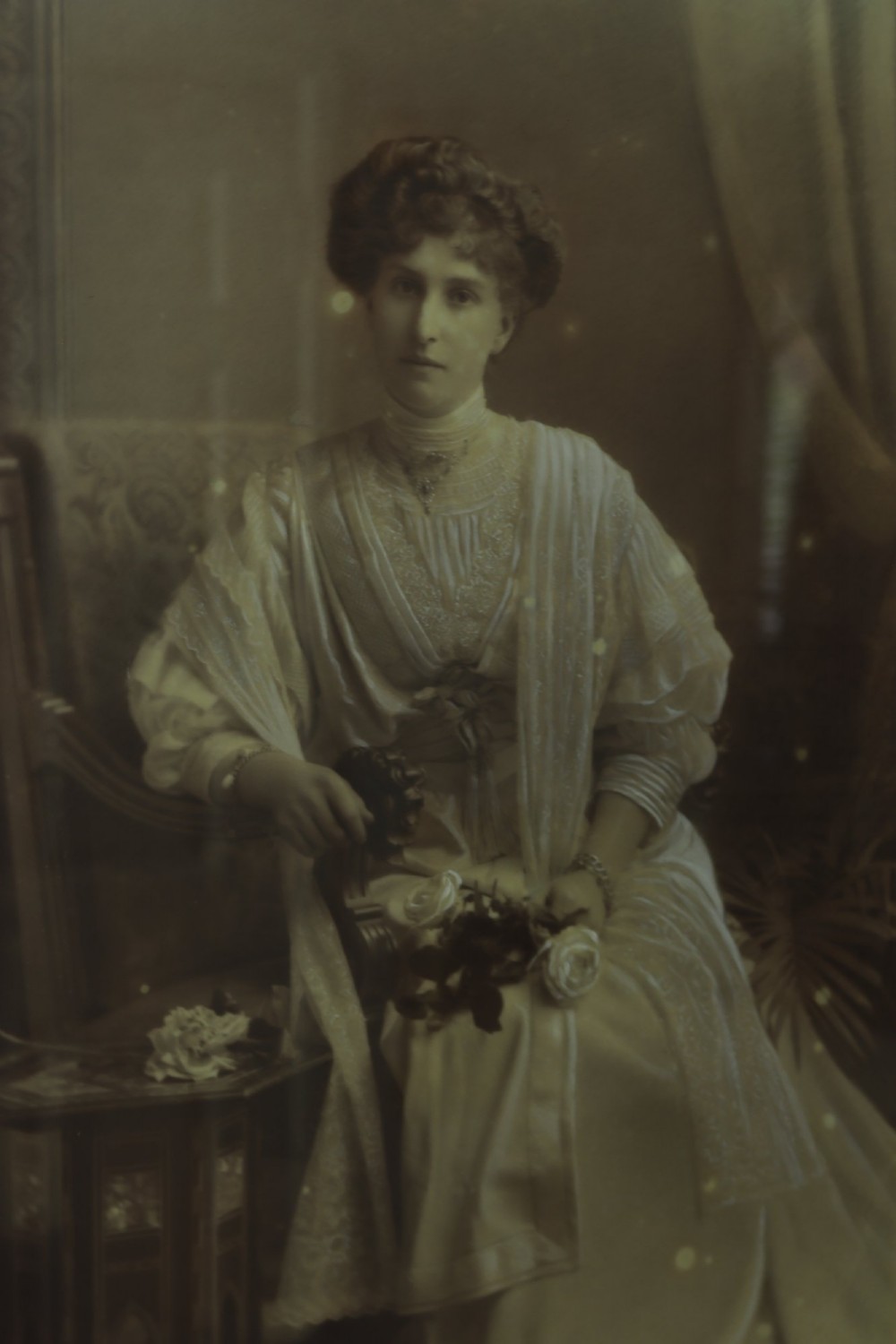 A monochrome Edwardian studio portrait photograph of a seated lady, mounted within a dark polished mahogany frame featuring a gilded inner slip. View VI
