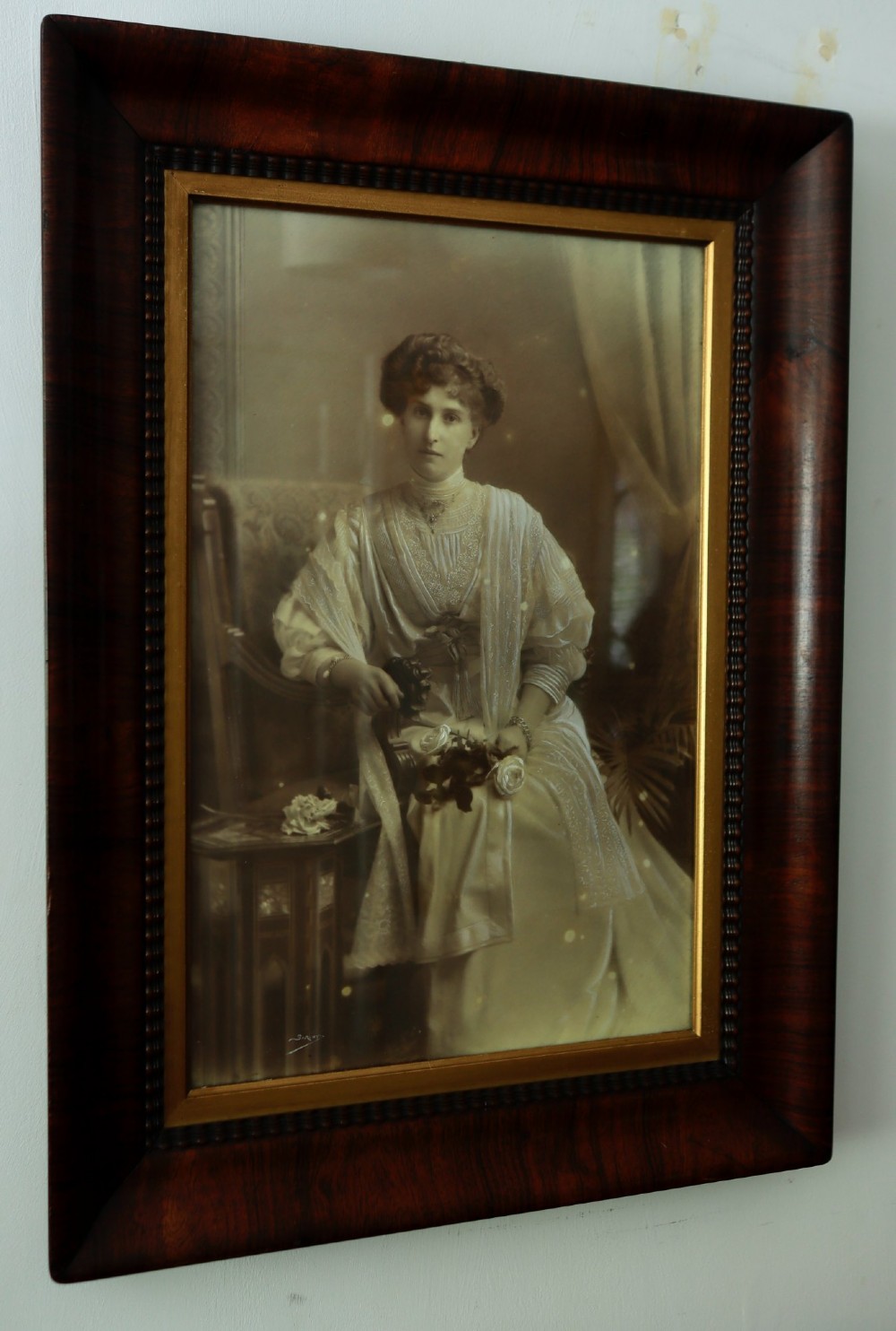 A monochrome Edwardian studio portrait photograph of a seated lady, mounted within a dark polished mahogany frame featuring a gilded inner slip. View VIII