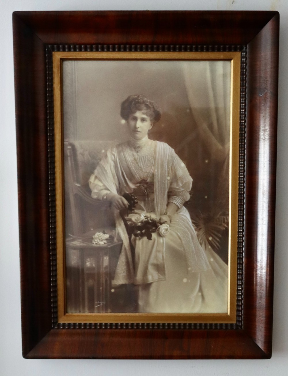 A monochrome Edwardian studio portrait photograph of a seated lady, mounted within a dark polished mahogany frame featuring a gilded inner slip. View X