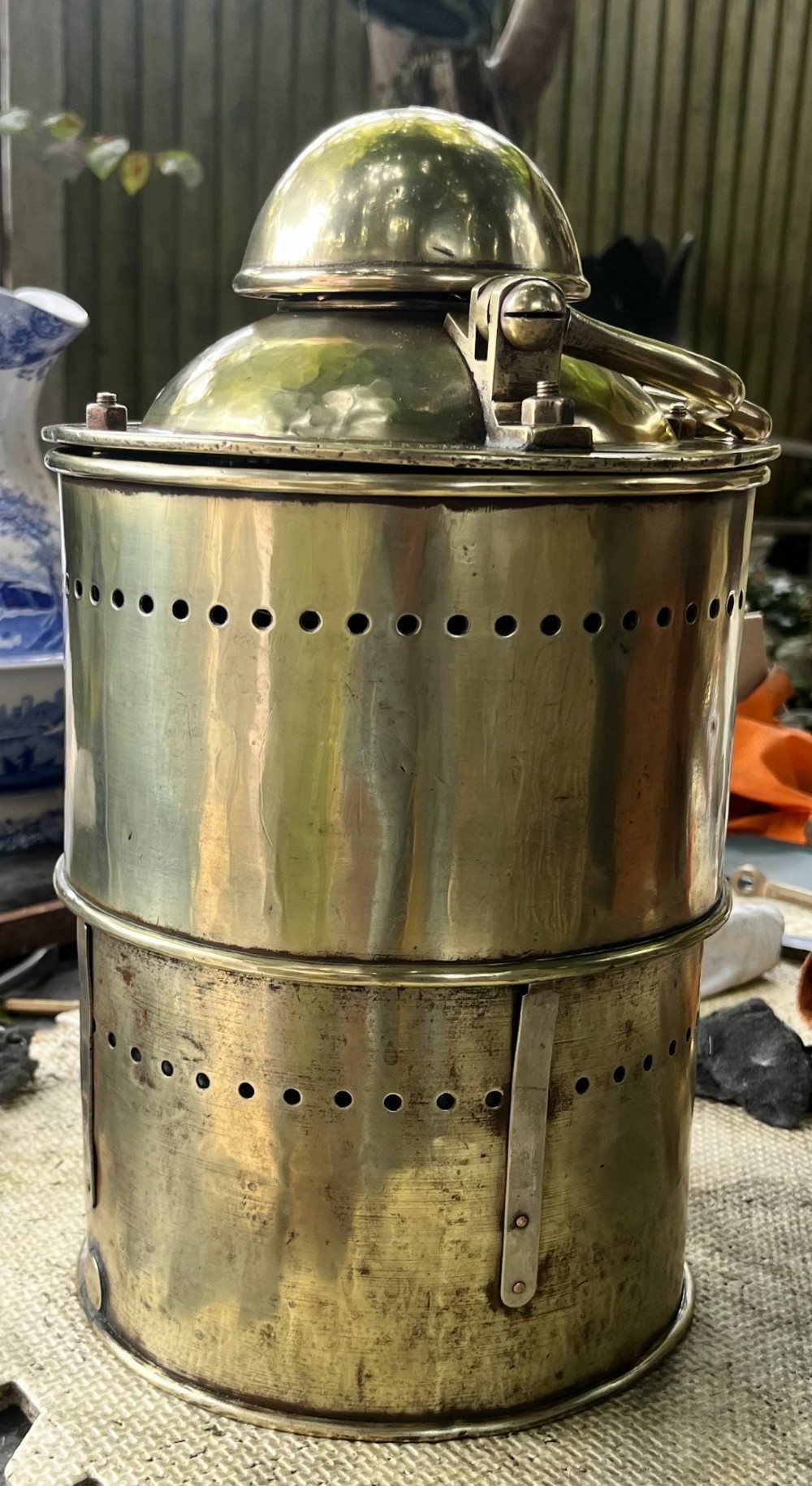 An antique brass wall lantern featuring a clear glass globe enclosed in a vented brass frame, suspended from a cast brass mascaron wall mount. View II