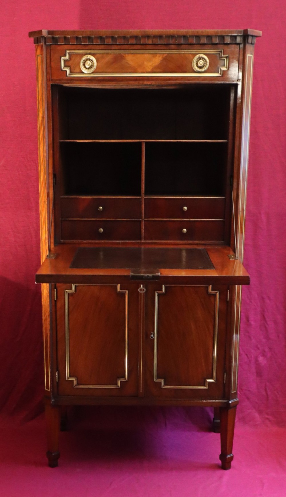 An antique mahogany escritoire featuring brass string inlay, a top drawer, a fall-front writing panel, and a two-door lower cupboard raised on tapered legs. View II