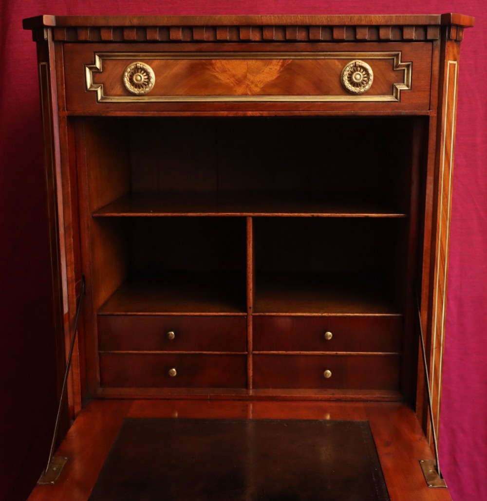 An antique mahogany escritoire featuring brass string inlay, a top drawer, a fall-front writing panel, and a two-door lower cupboard raised on tapered legs. View IV