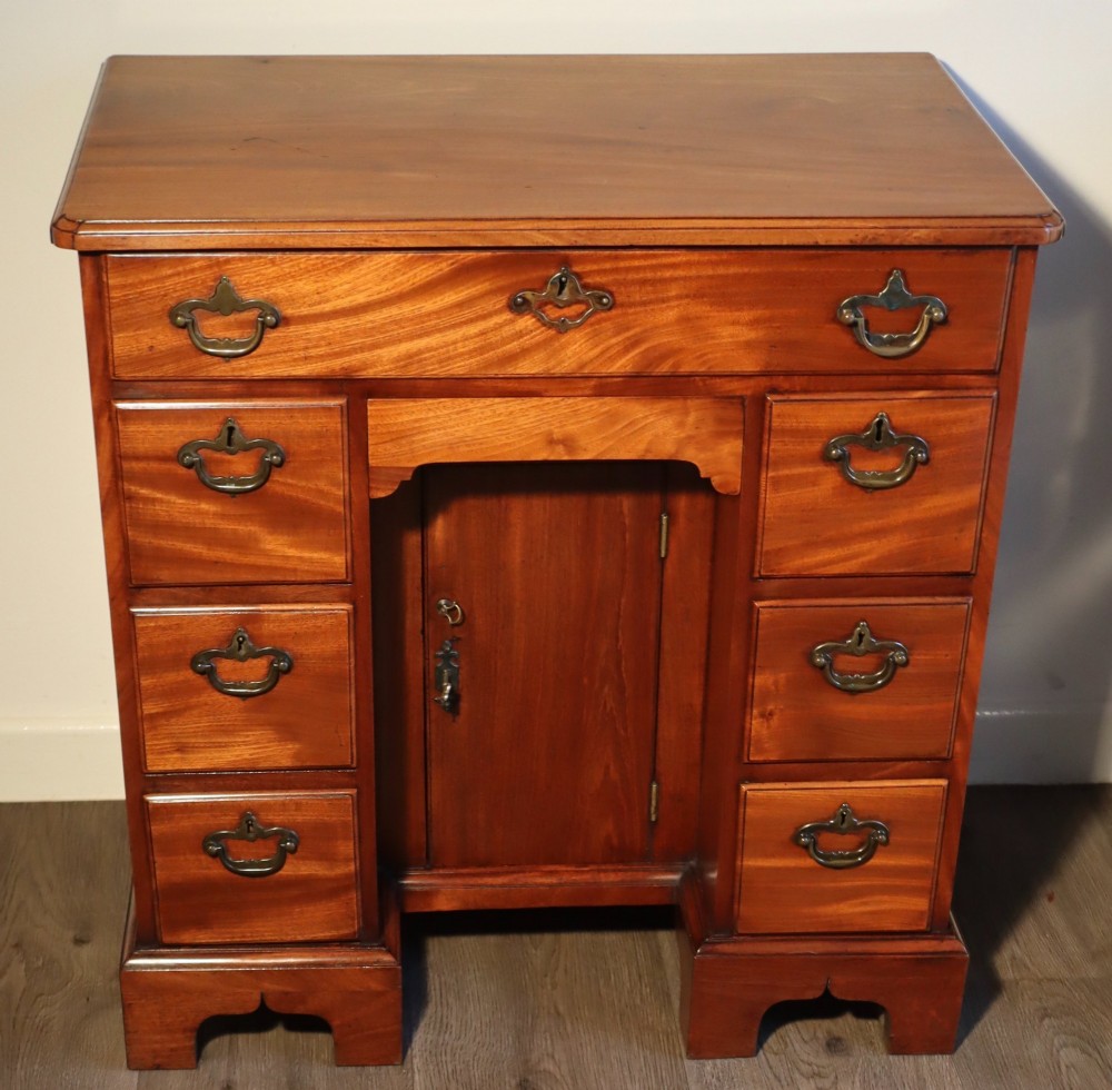 A Georgian mahogany kneehole dressing table featuring multiple drawers with brass swan-neck handles, a recessed central cupboard, and bracket feet. View II