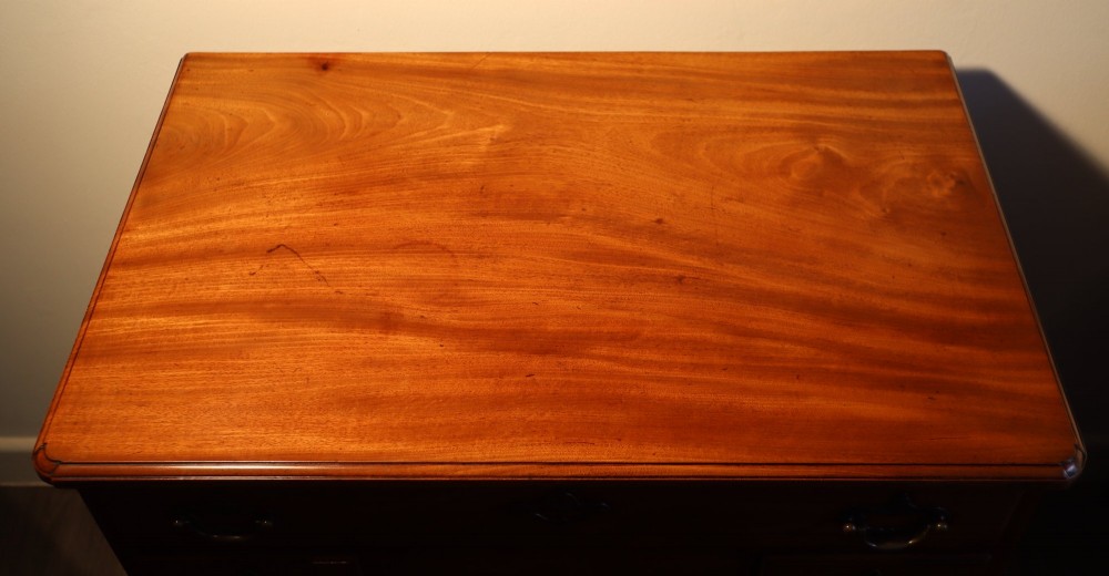 A Georgian mahogany kneehole dressing table featuring multiple drawers with brass swan-neck handles, a recessed central cupboard, and bracket feet. View III