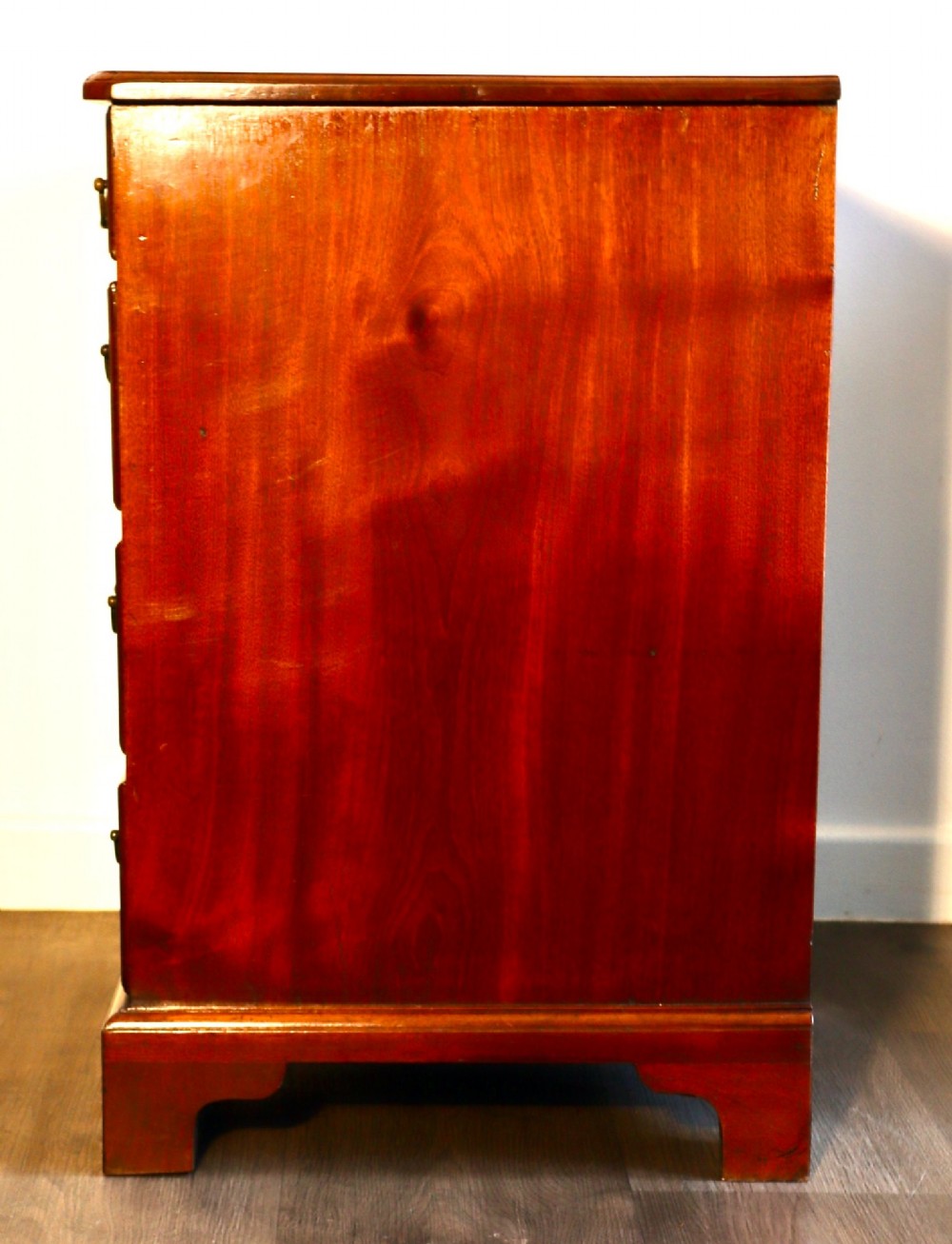 A Georgian mahogany kneehole dressing table featuring multiple drawers with brass swan-neck handles, a recessed central cupboard, and bracket feet. View IV