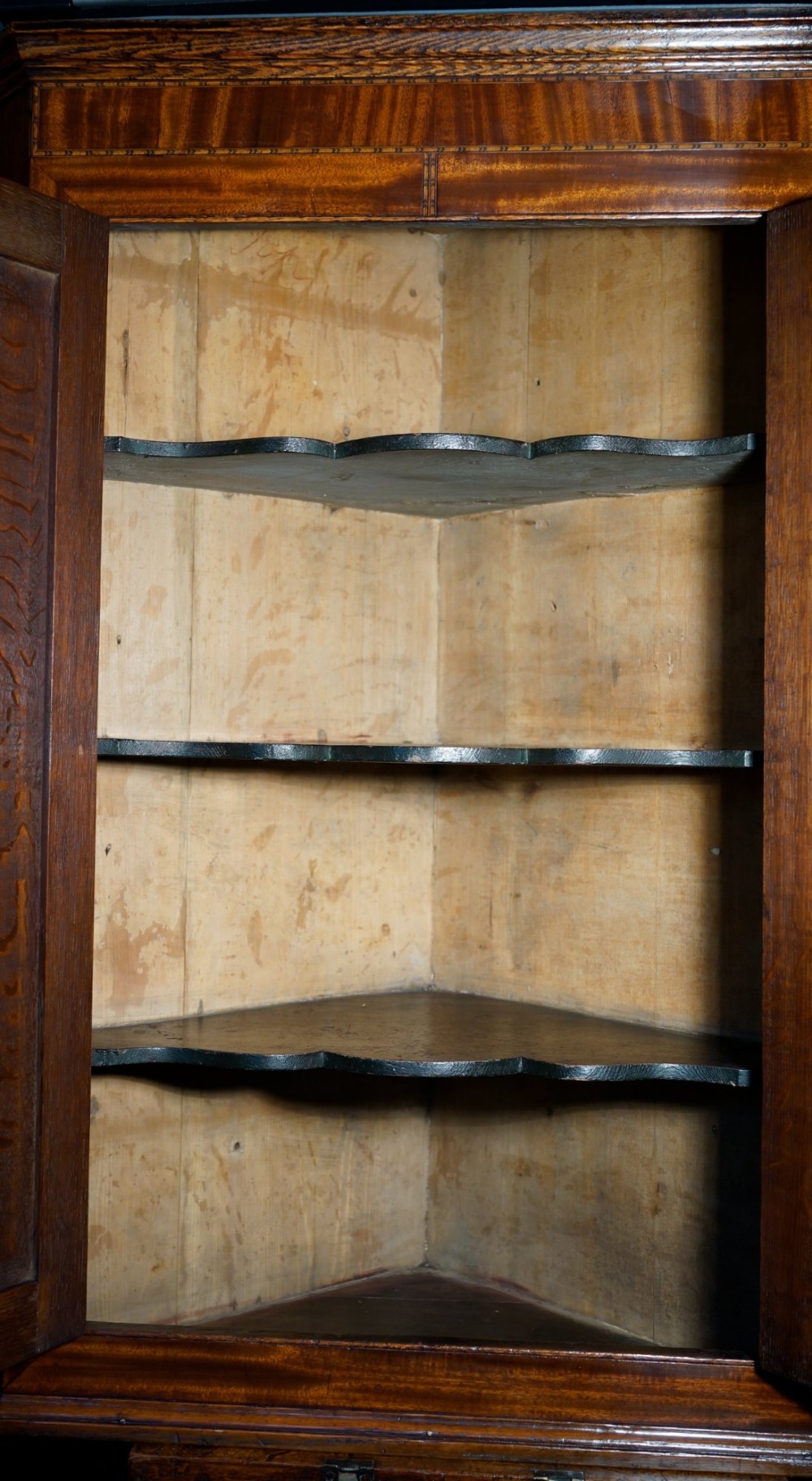 An antique oak hanging corner cupboard with twin panelled doors, inlaid central motifs, bone keyhole escutcheons, and a moulded top cornice. View III
