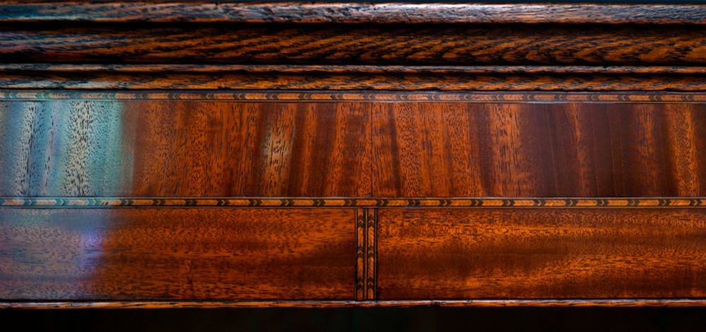 An antique oak hanging corner cupboard with twin panelled doors, inlaid central motifs, bone keyhole escutcheons, and a moulded top cornice. View IV