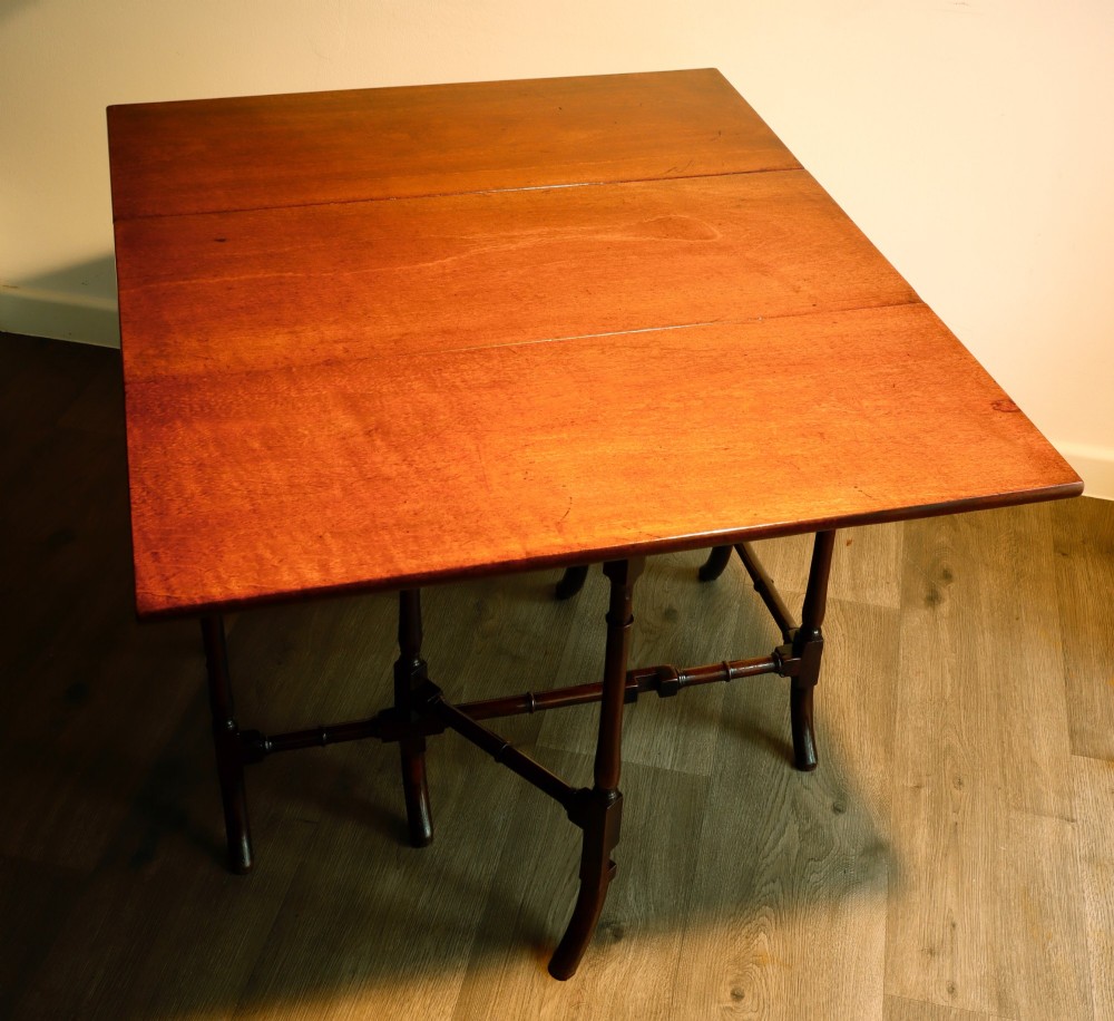 A Georgian mahogany spider leg tea table featuring two hinged drop leaves and slender turned gateleg supports connected by stretchers. View II
