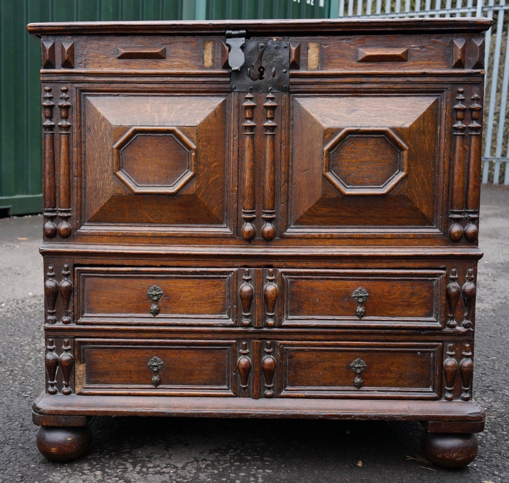 An antique dark oak mule chest featuring geometric fielded panels, turned split-baluster mouldings, lower drawers, and bun feet. View II