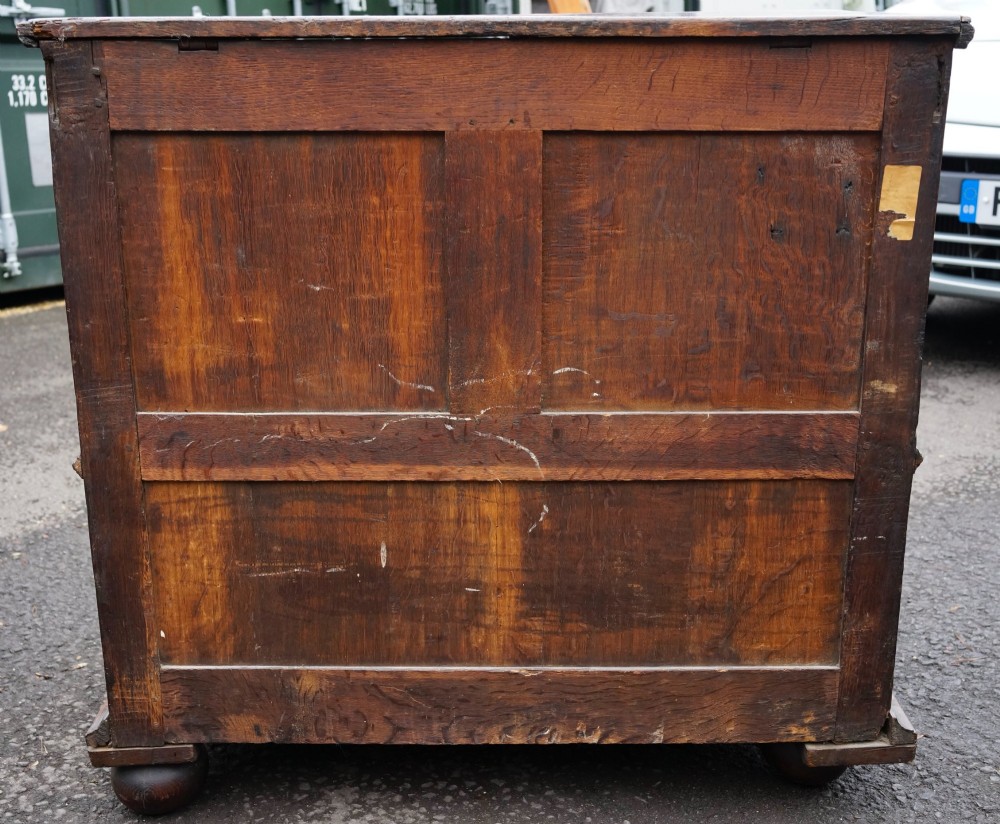 An antique dark oak mule chest featuring geometric fielded panels, turned split-baluster mouldings, lower drawers, and bun feet. View IV