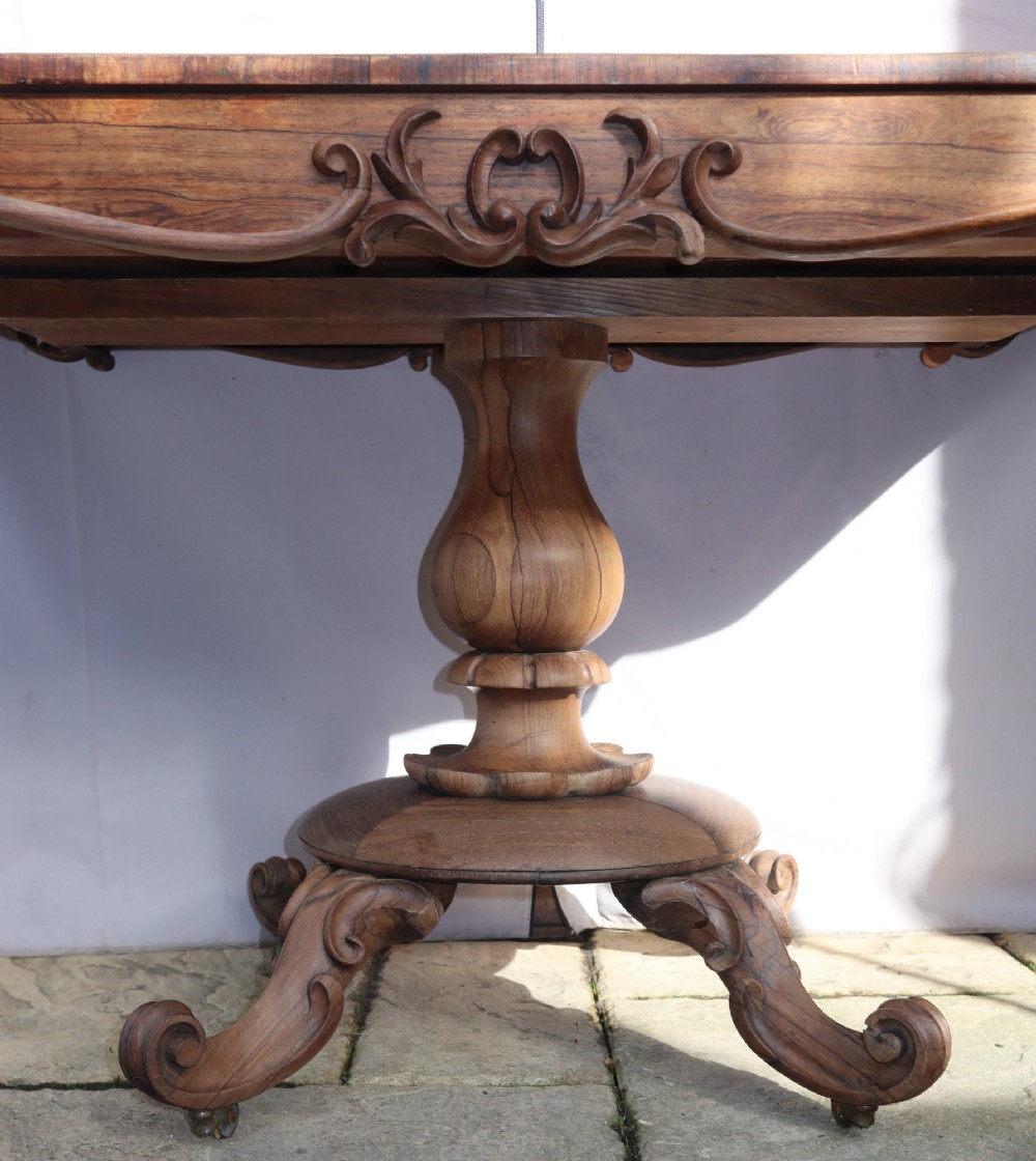 A Victorian rosewood centre table with a rectangular top, carved frieze, a central turned bulbous pedestal, and scroll legs on castors. View III