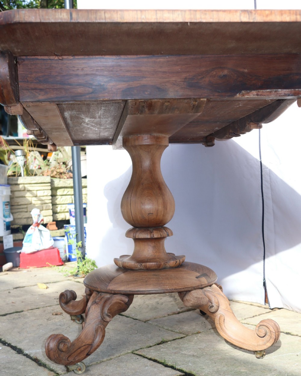 A Victorian rosewood centre table with a rectangular top, carved frieze, a central turned bulbous pedestal, and scroll legs on castors. View IV