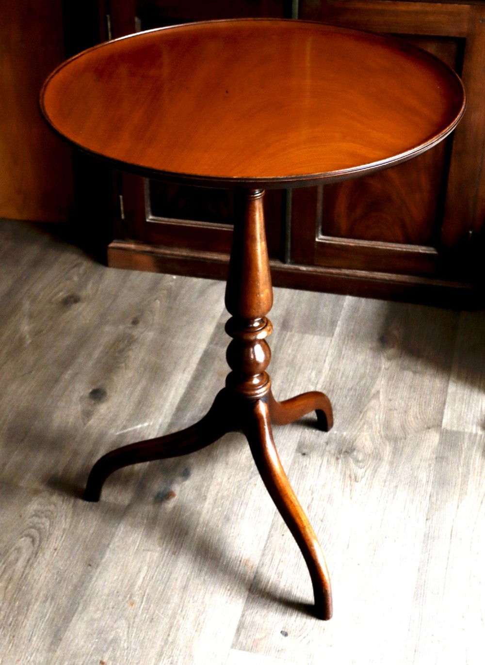 A mahogany tilt-top tripod table featuring a circular dished top, turned central column, and three cabriole legs. View IV